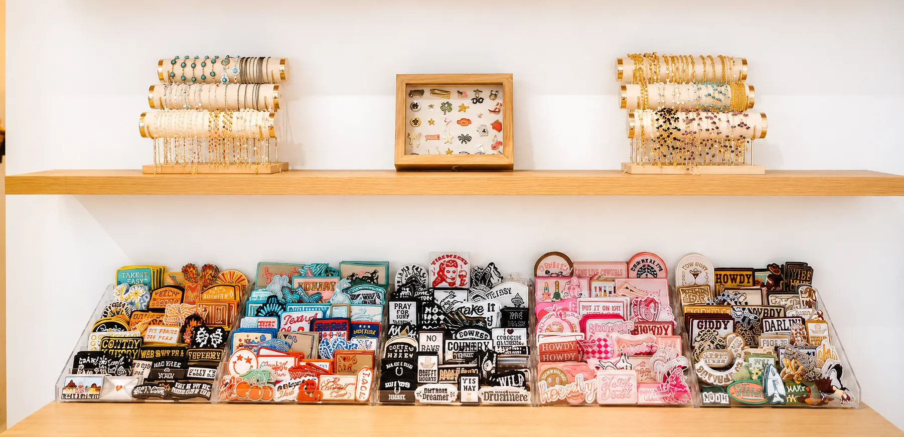 Wall of hundreds of embroidered patches and charm bracelets at a Brimstreet custom hat bar display